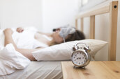 couple-sleeping-bed-with-alarm-clock-wooden-desk_23-2147911783.jpg